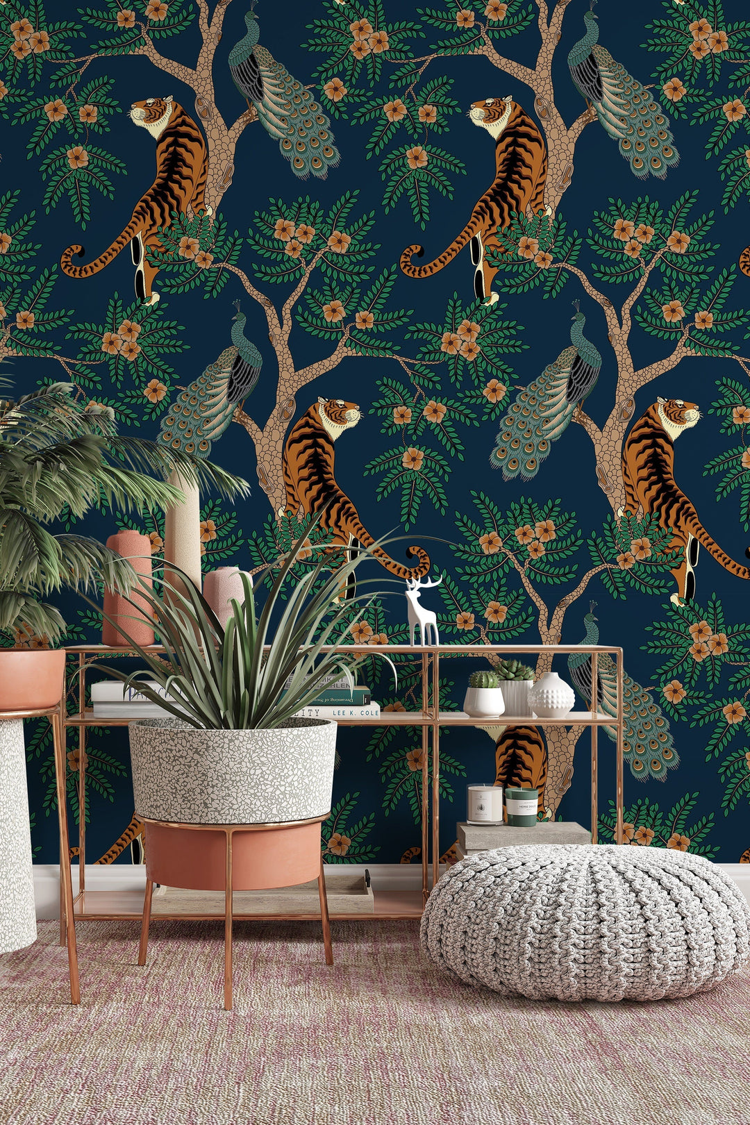 Dark navy wallpaper featuring stylized tigers and peacocks perched on flowering tree branches, with green foliage and warm orange blossoms in a repeating exotic pattern, shown in a modern interior setting.