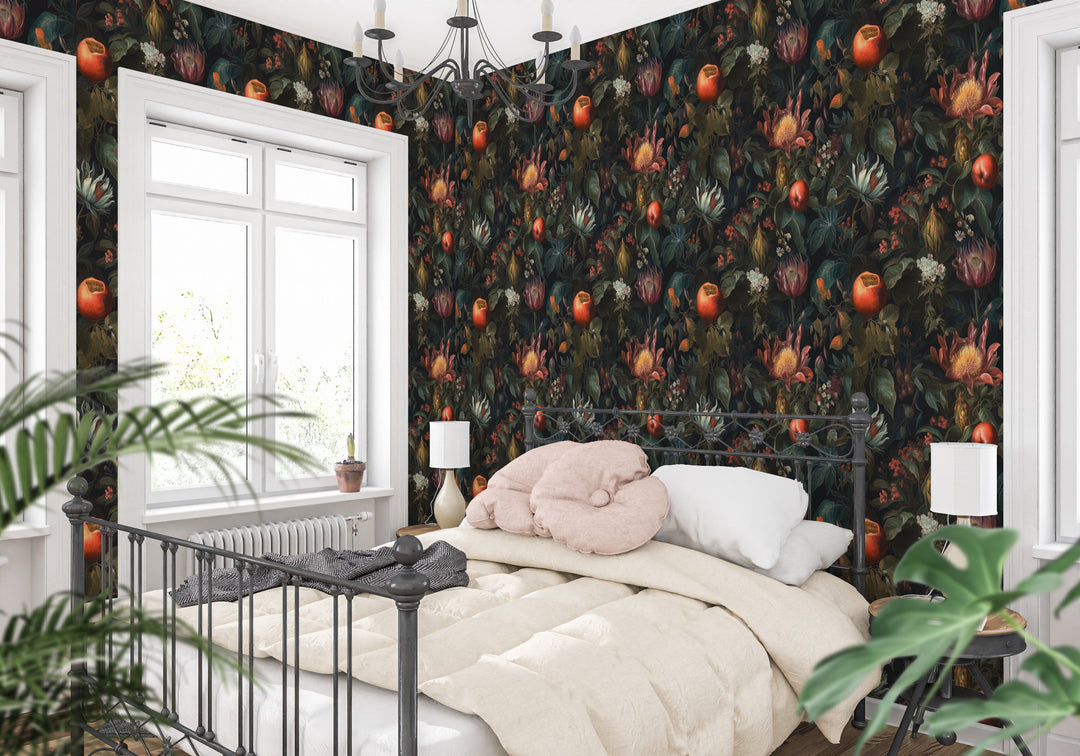 Dark botanical wallpaper with red and orange fruit, exotic flowers, and leafy foliage featured in a bright bedroom with a white bed and black metal frame.