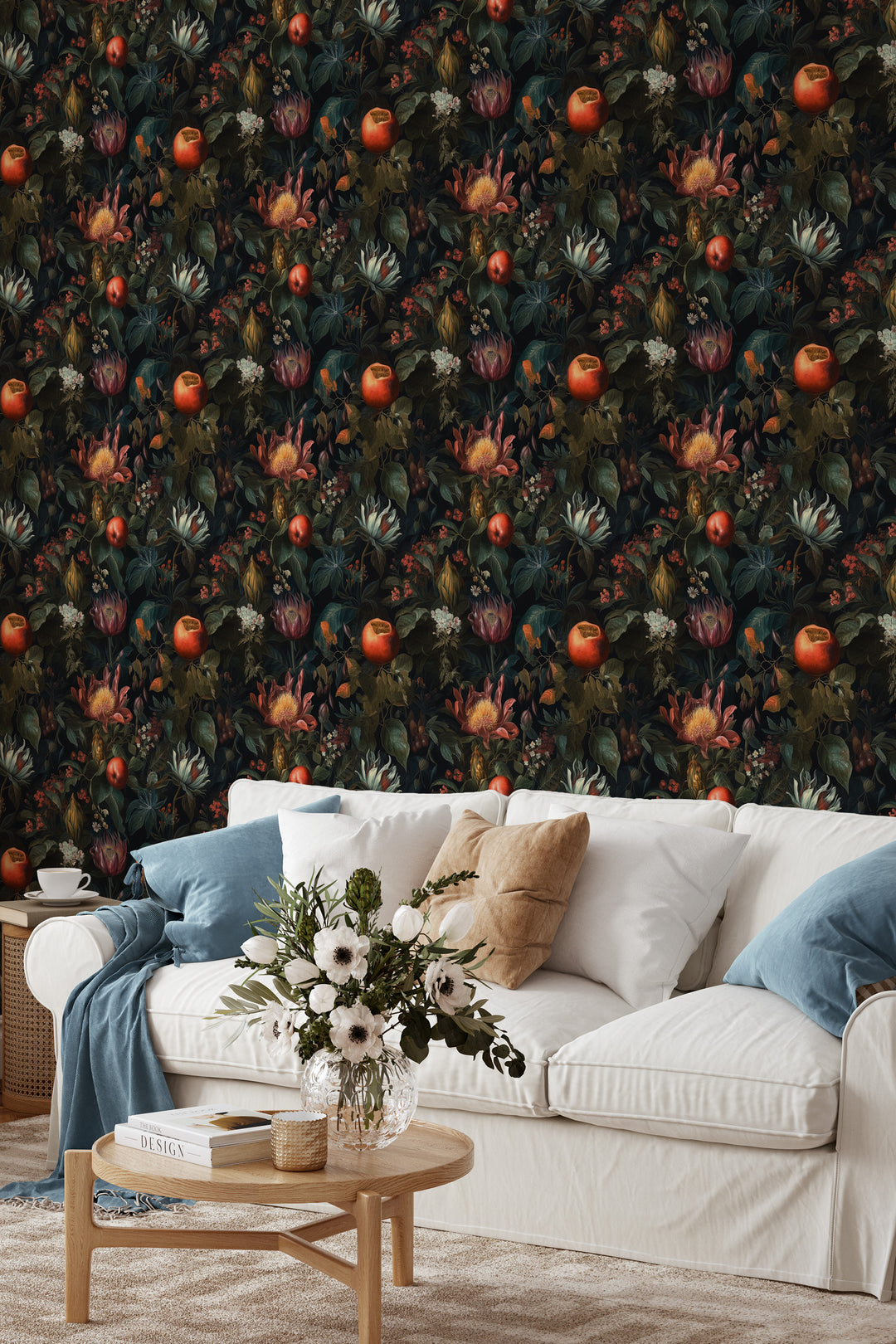 Dark botanical wallpaper with red and orange fruit, tropical flowers, and leafy foliage behind a white sofa and wooden coffee table.
