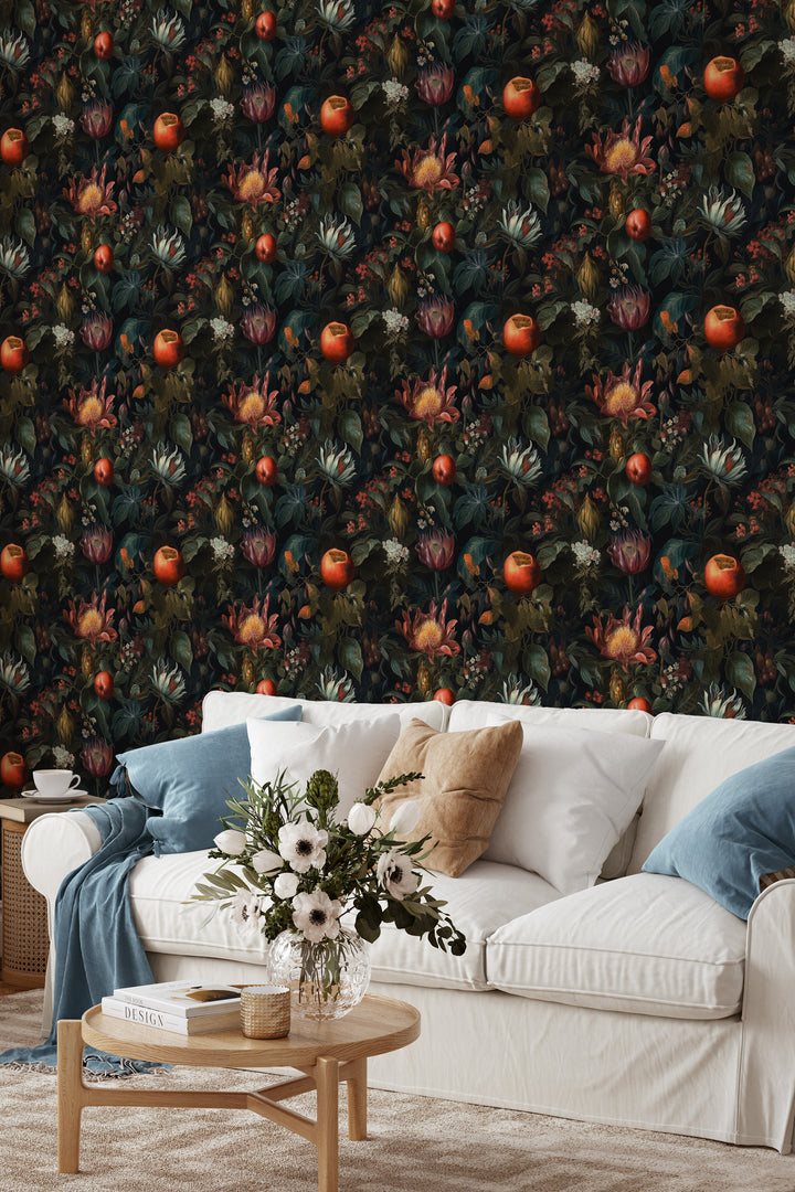 Dark botanical wallpaper with red and orange fruit, tropical flowers, and leafy foliage behind a white sofa and wooden coffee table.