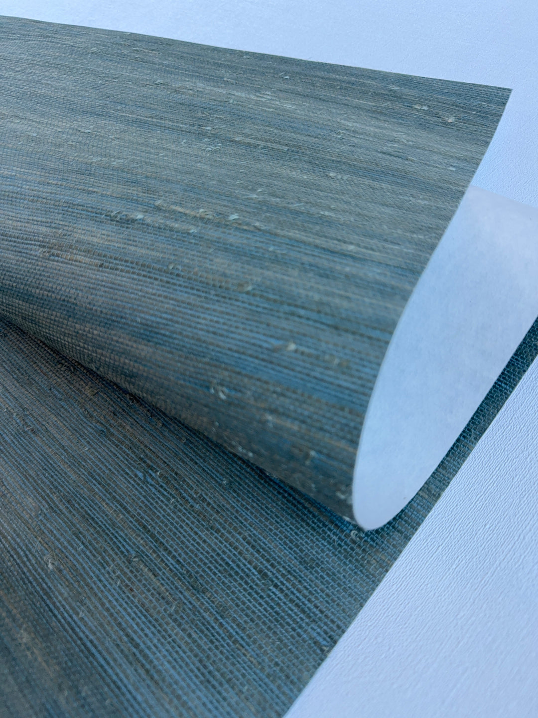 Handwoven Super Hemp 42121 natural grasscloth wallpaper in muted blue green, close-up showing horizontal weave and natural fiber knots