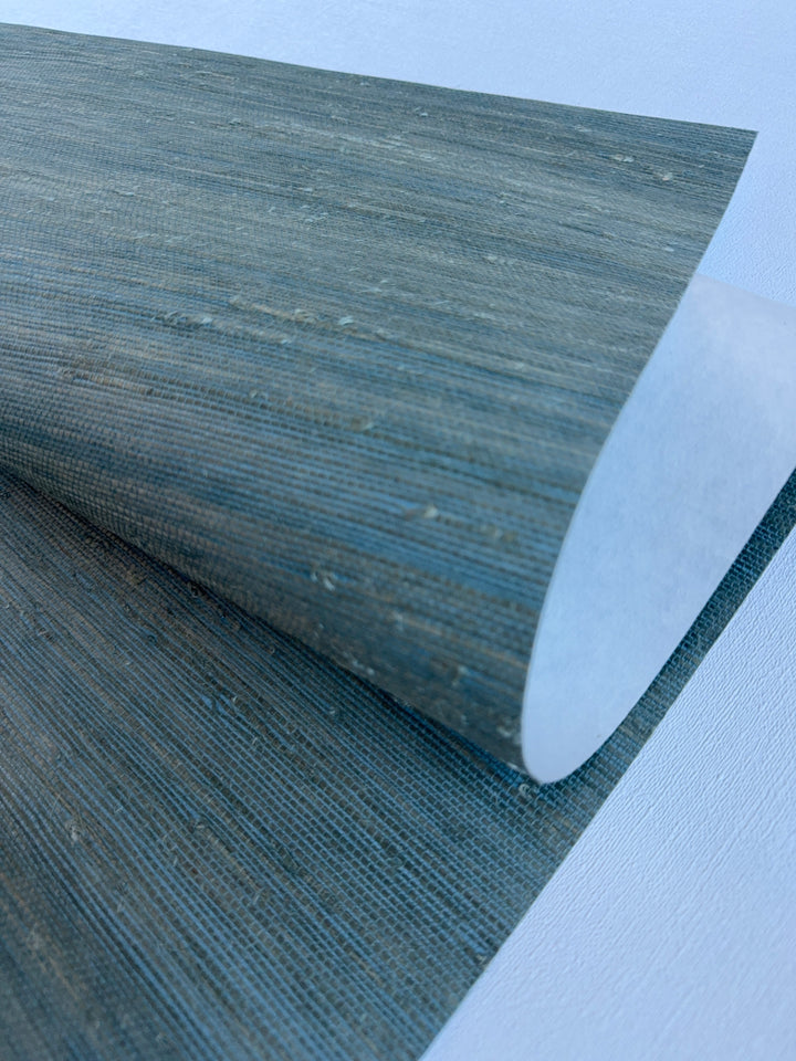 Handwoven Super Hemp 42121 natural grasscloth wallpaper in muted blue green, close-up showing horizontal weave and natural fiber knots