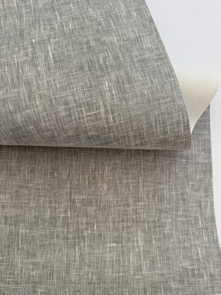Handcrafted natural linen grasscloth wallpaper with light woven texture, close-up view showing real linen fibers and soft neutral tone