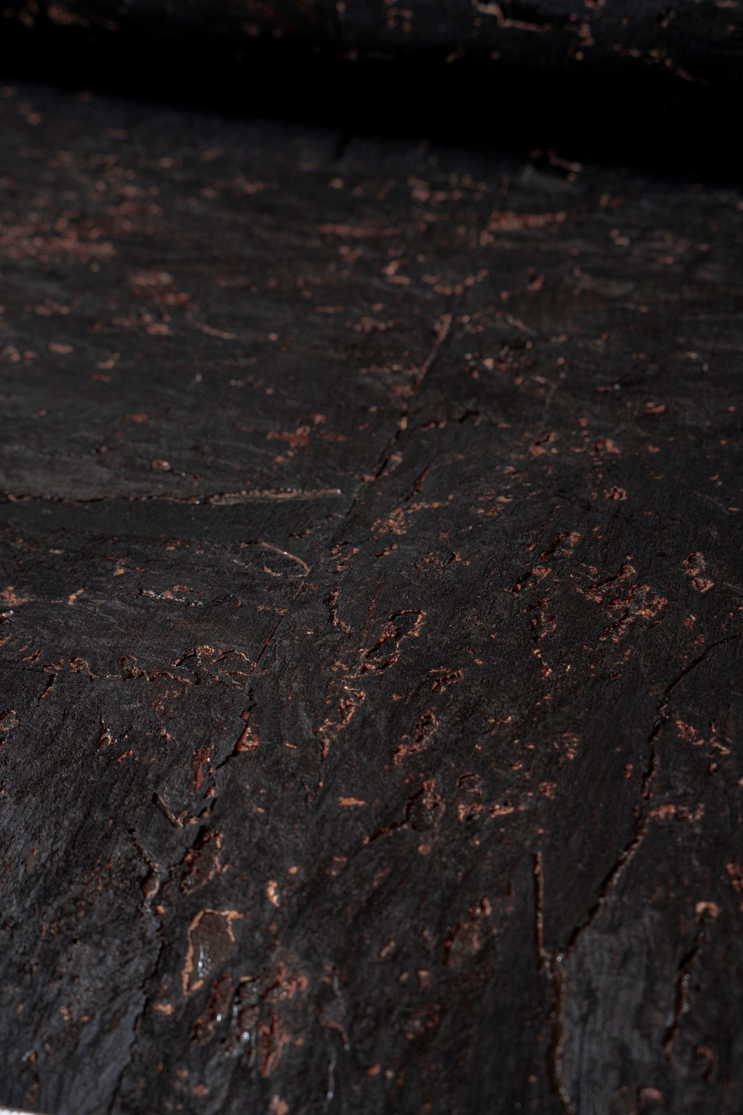 Close-up of dark, textured surface with small cracks and imperfections