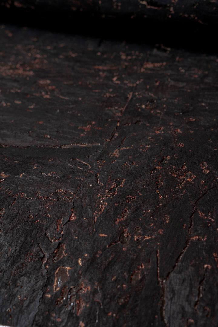 Close-up of dark, textured surface with small cracks and imperfections