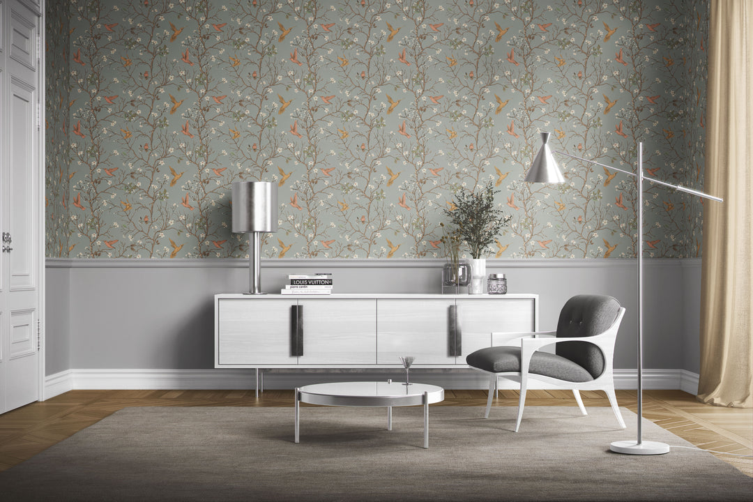 Sage gray hummingbird wallpaper with flowering branches and colorful birds featured as an accent wall in a modern mid-century living room.