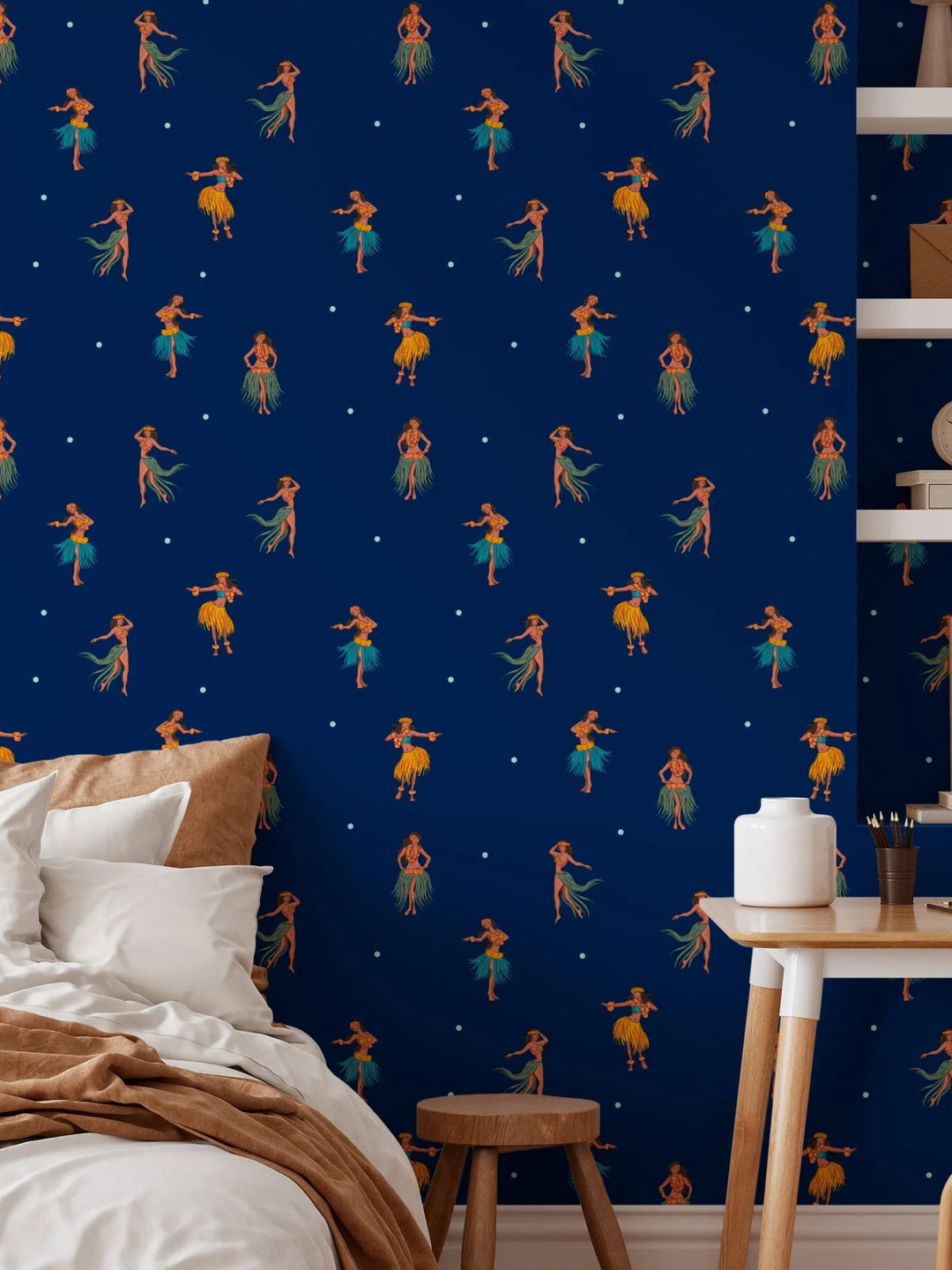 a bedroom with a blue wall decorated with a repeating pattern of hula dancers in yellow and green outfits. The room has a bed, a table, and a shelf with various items on it.