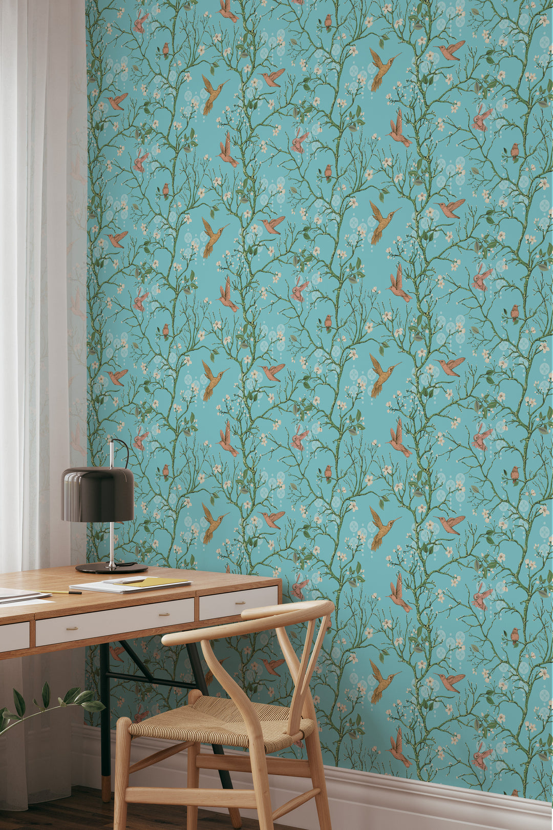 Aqua blue hummingbird wallpaper with delicate floral branches behind a wooden desk and chair in a stylish home office.