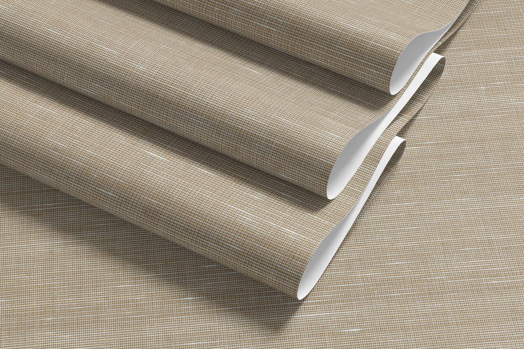 Rolled sheets of soft beige faux abaca grasscloth wallpaper with fine white grid pattern, showing texture and layering.