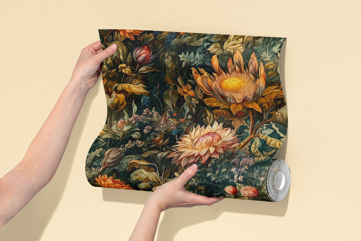 Dark green dahlia wallpaper with vintage orange and cream botanical flowers pattern shown on a wallpaper sample roll
