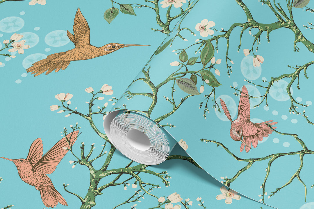 Aqua blue hummingbird wallpaper with birds and flowering branches shown on a rolled wallpaper sample.