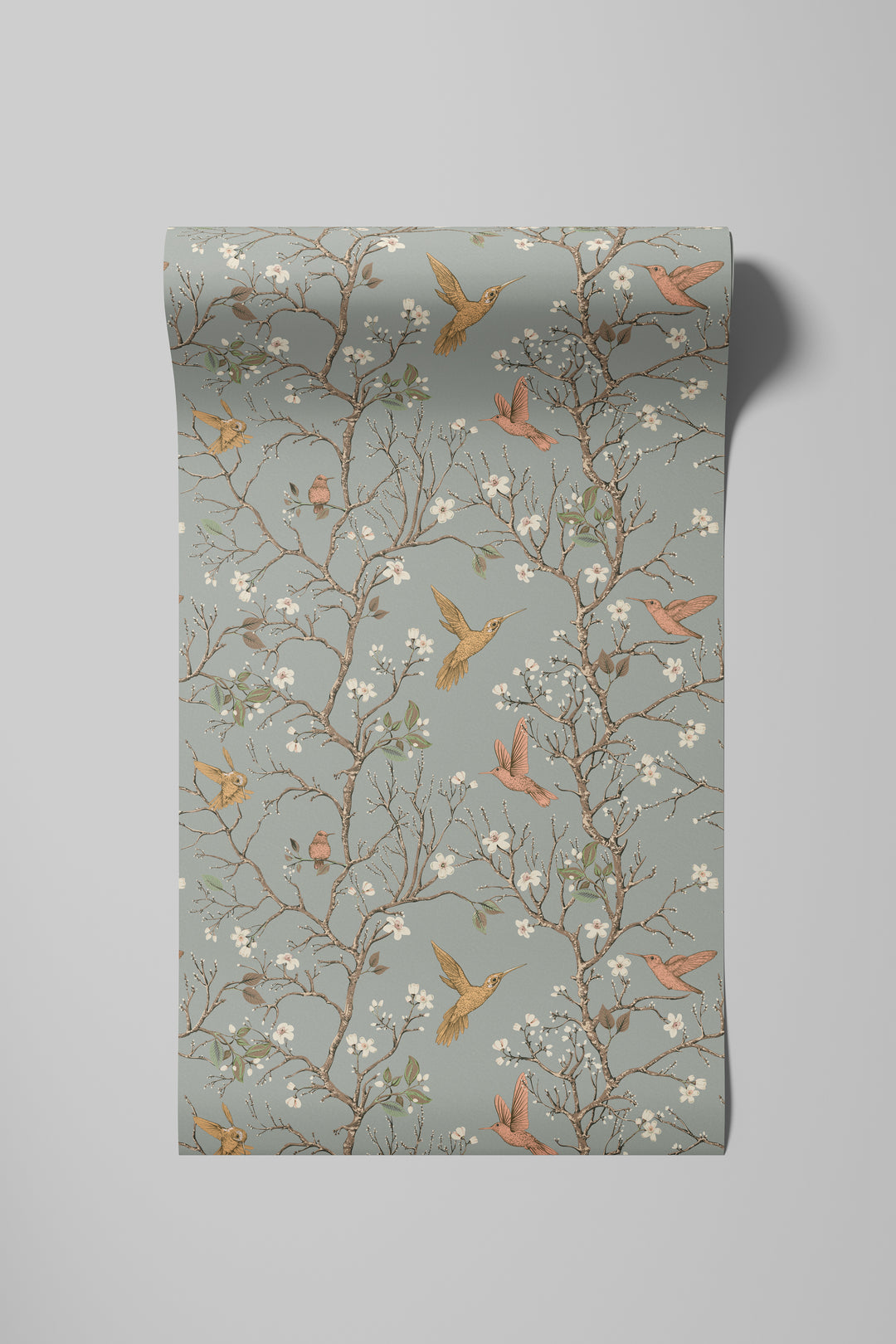 Sage gray hummingbird wallpaper with flowering branches and colorful birds displayed on a rolled wallpaper sample.