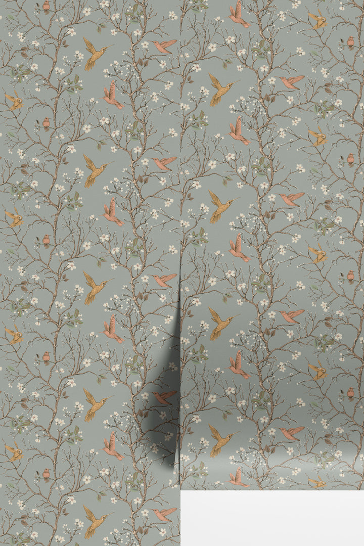 Sage gray hummingbird wallpaper with flowering branches and colorful birds displayed in overlapping wallpaper sheets.